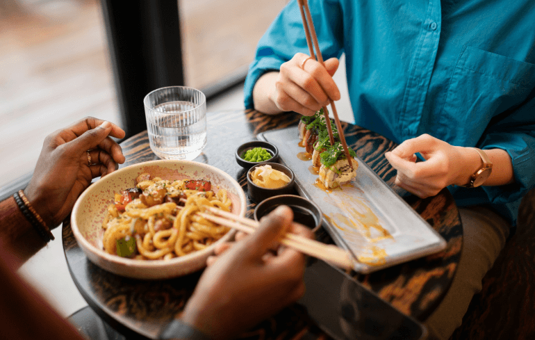 Two people eating Asian food at a restaurant