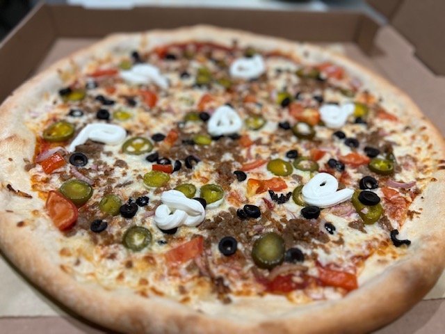 A pizza topped with ground meat and vegetables