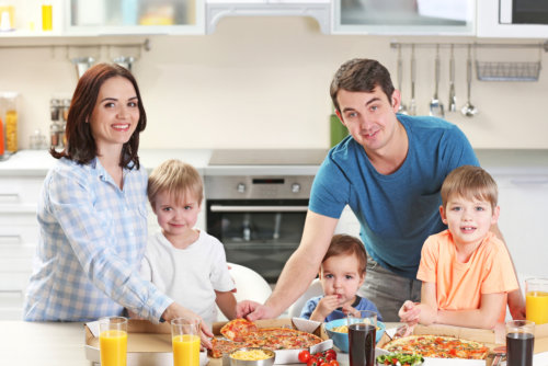 A happy family preparing or eating pizza in a kitchen