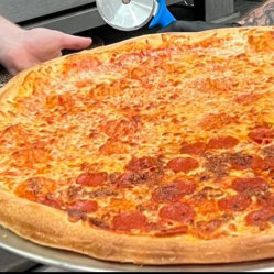 Person cutting a large pepperoni and cheese pizza- Crustini pizza