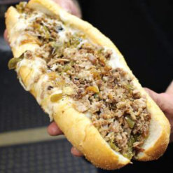 A Philly cheesesteak sandwich held in hands- Crustini pizza
