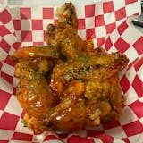 A serving of saucy chicken wings in a paper basket- Crustini pizza